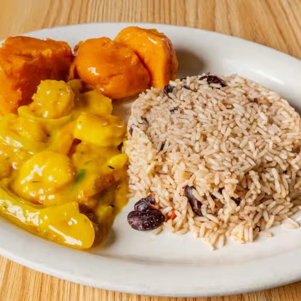 A Caribbean meal with rice and beans, yellow curry, and two pieces of sweet potato.
